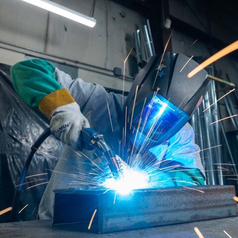 sparks flying while person in helmet welds
