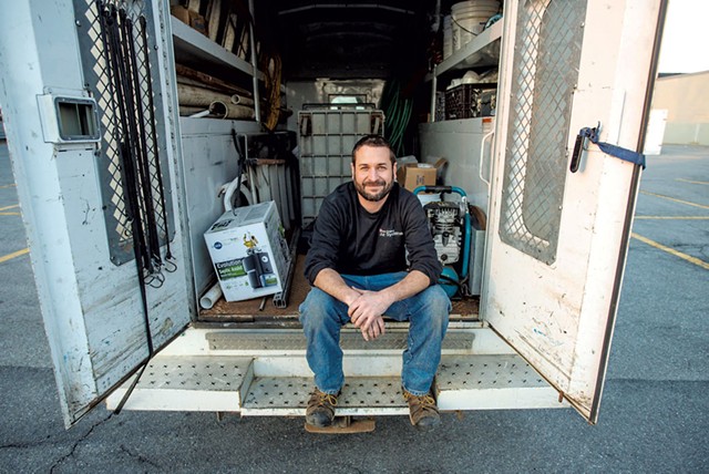 person sitting and smiling at back of open service van
