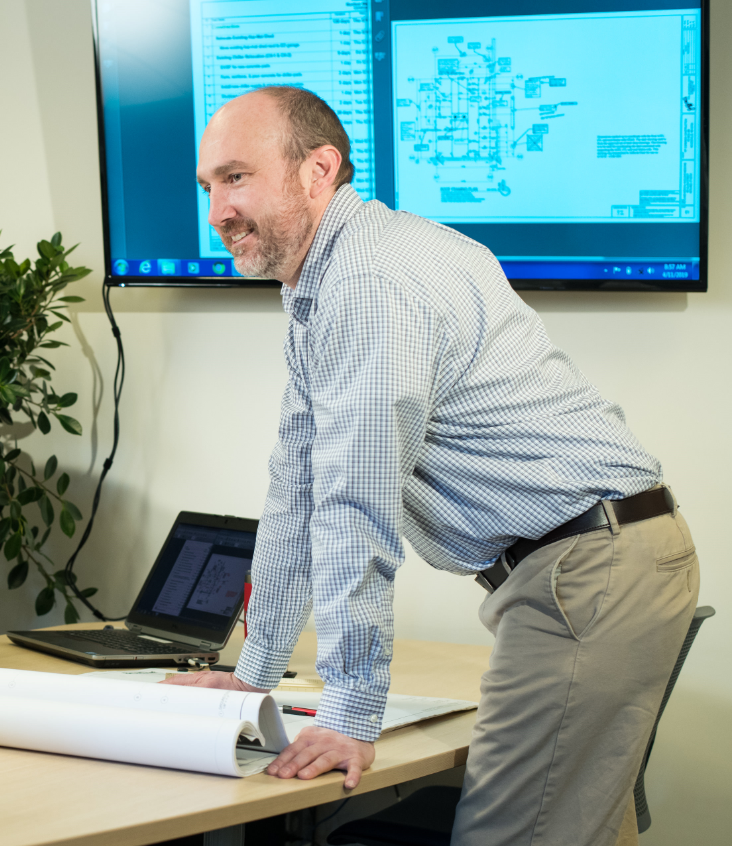 person smiling while leaning over design plans on table