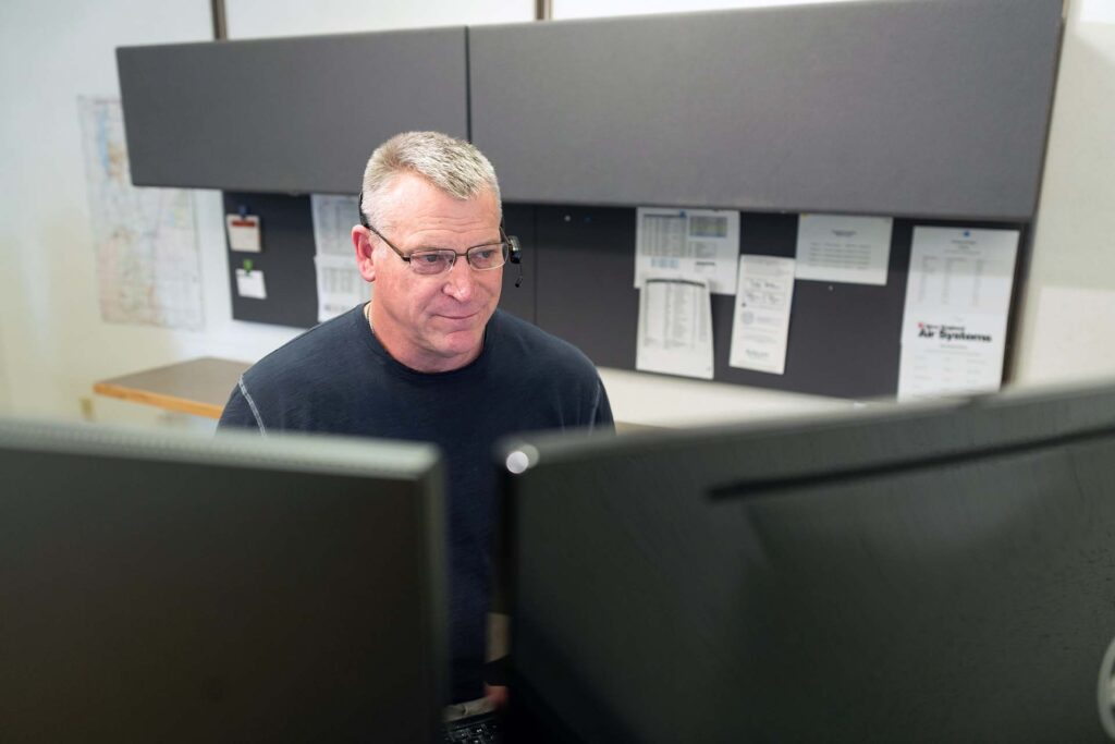 employee sitting at desk while working on computer monitors